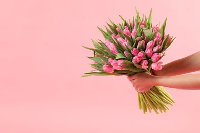 Photo of Woman with bouquet of beautiful tulips on pink background, closeup. Space for text