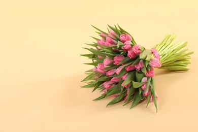 Photo of Bouquet of beautiful tulips on beige background, space for text