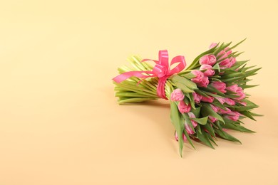 Photo of Bouquet of beautiful tulips on beige background, space for text