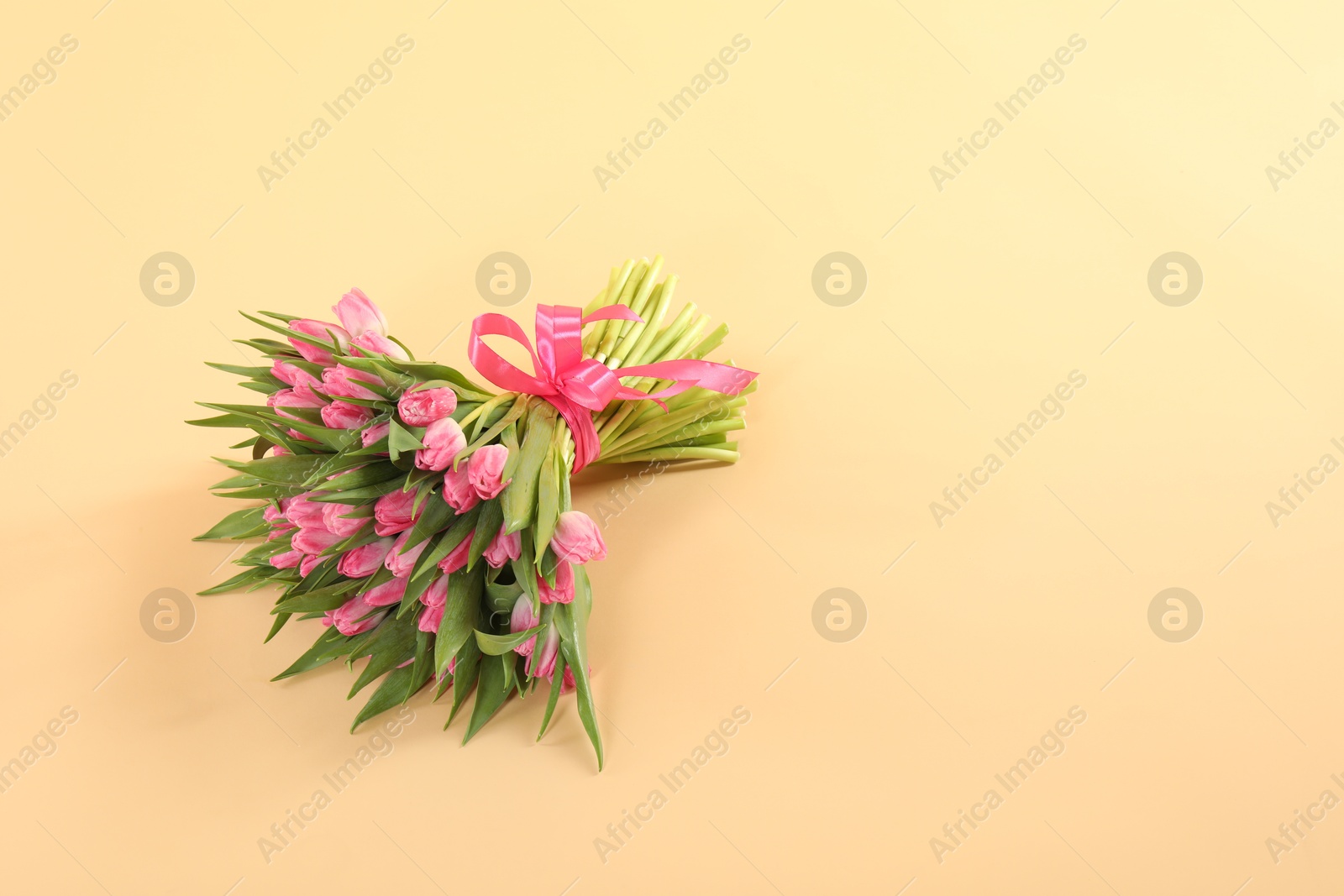 Photo of Bouquet of beautiful tulips on beige background, space for text