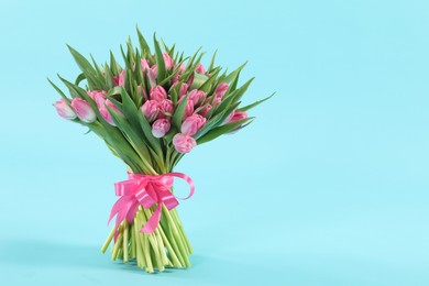 Photo of Bouquet of beautiful tulips on light blue background, space for text