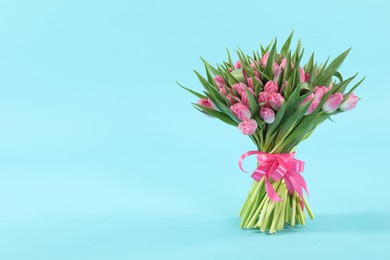 Photo of Bouquet of beautiful tulips on light blue background, space for text