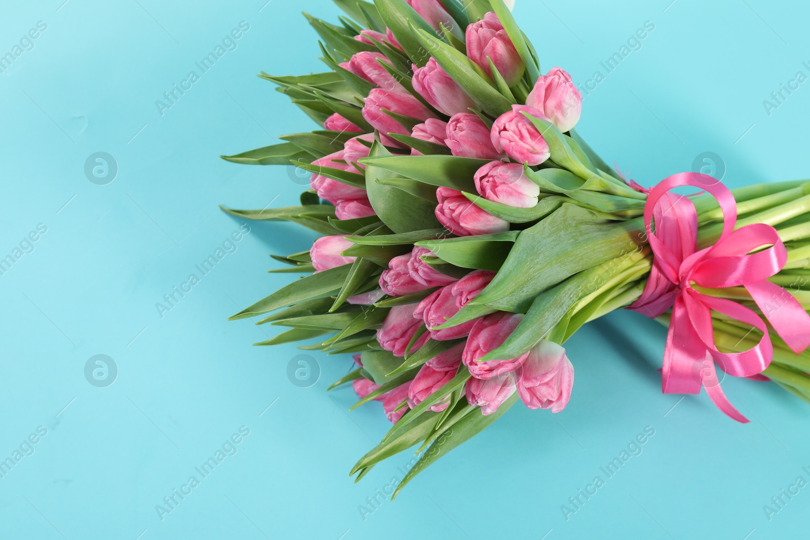 Photo of Bouquet of beautiful tulips on light blue background, top view. Space for text