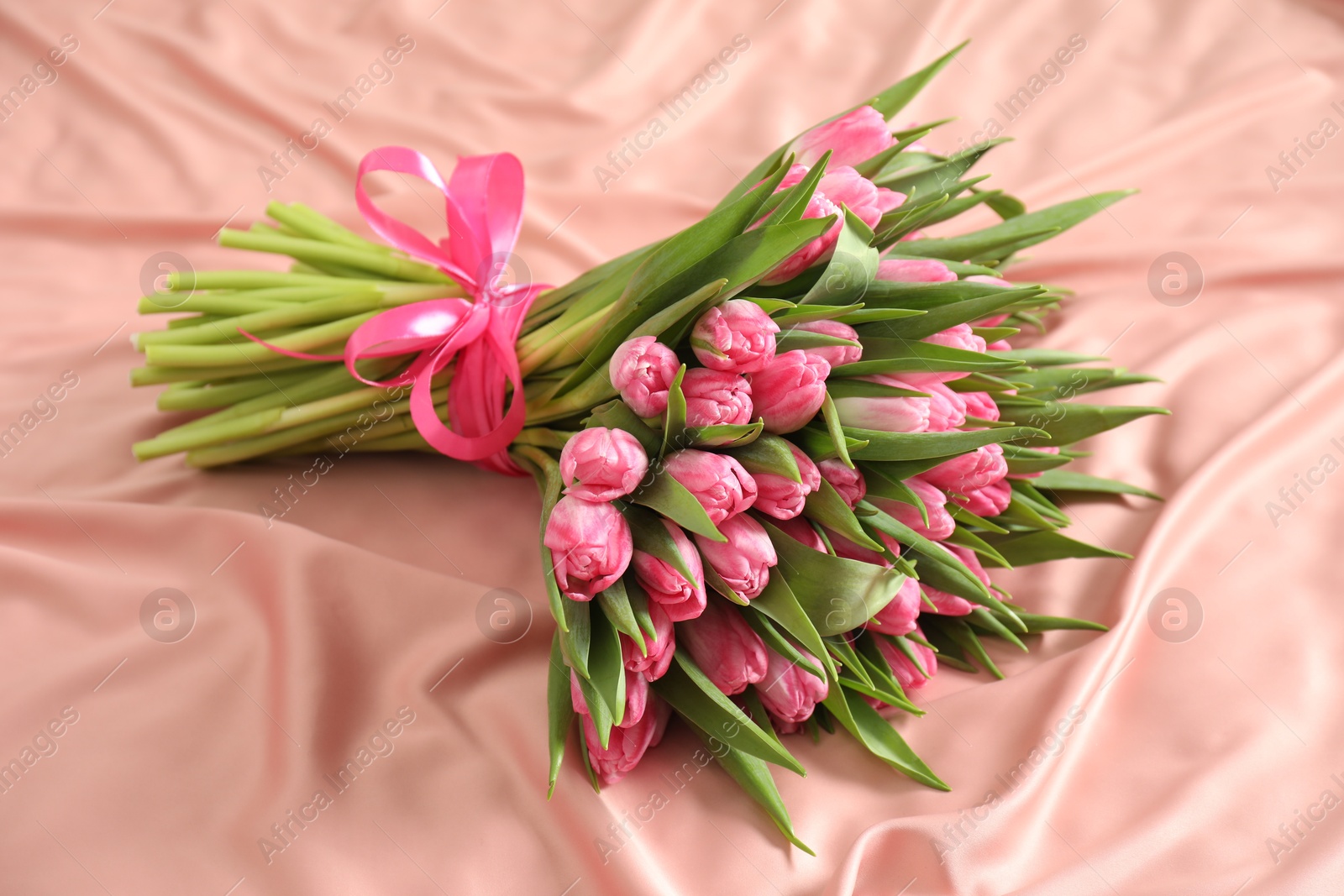 Photo of Bouquet of beautiful tulips on silk fabric