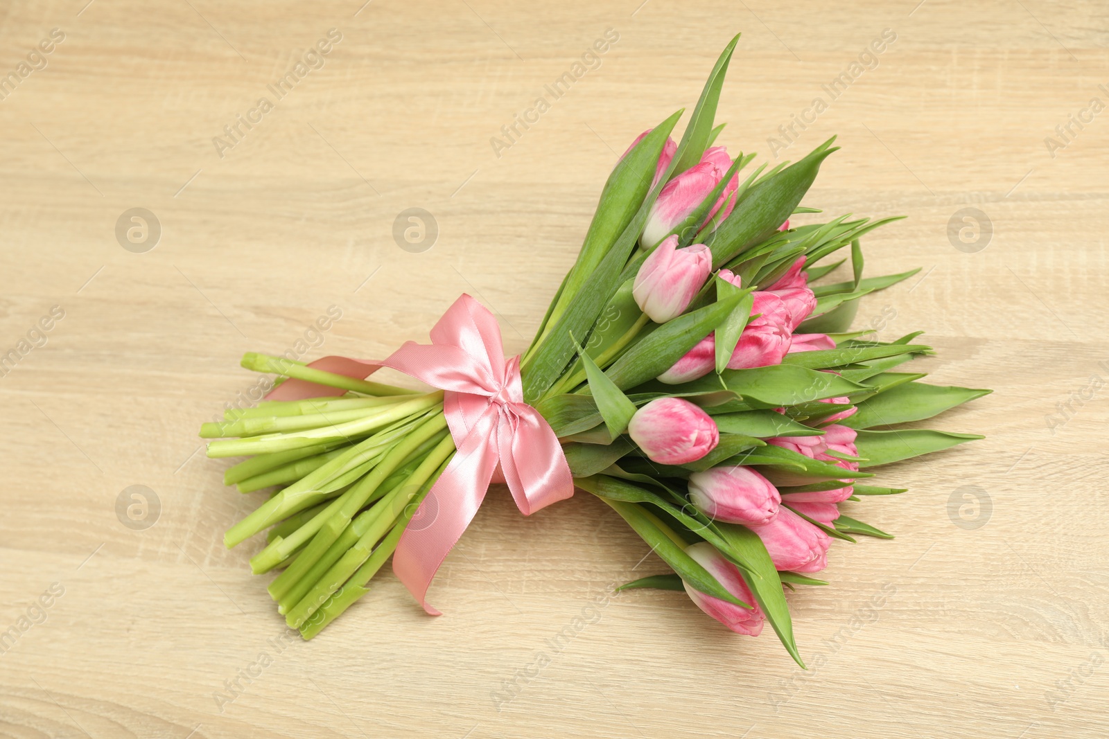 Photo of Bouquet of beautiful tulips on wooden table, above view