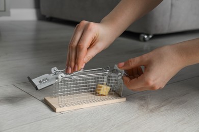 Photo of Woman with metal mouse trap indoors, closeup