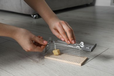 Photo of Woman with metal mouse trap indoors, closeup