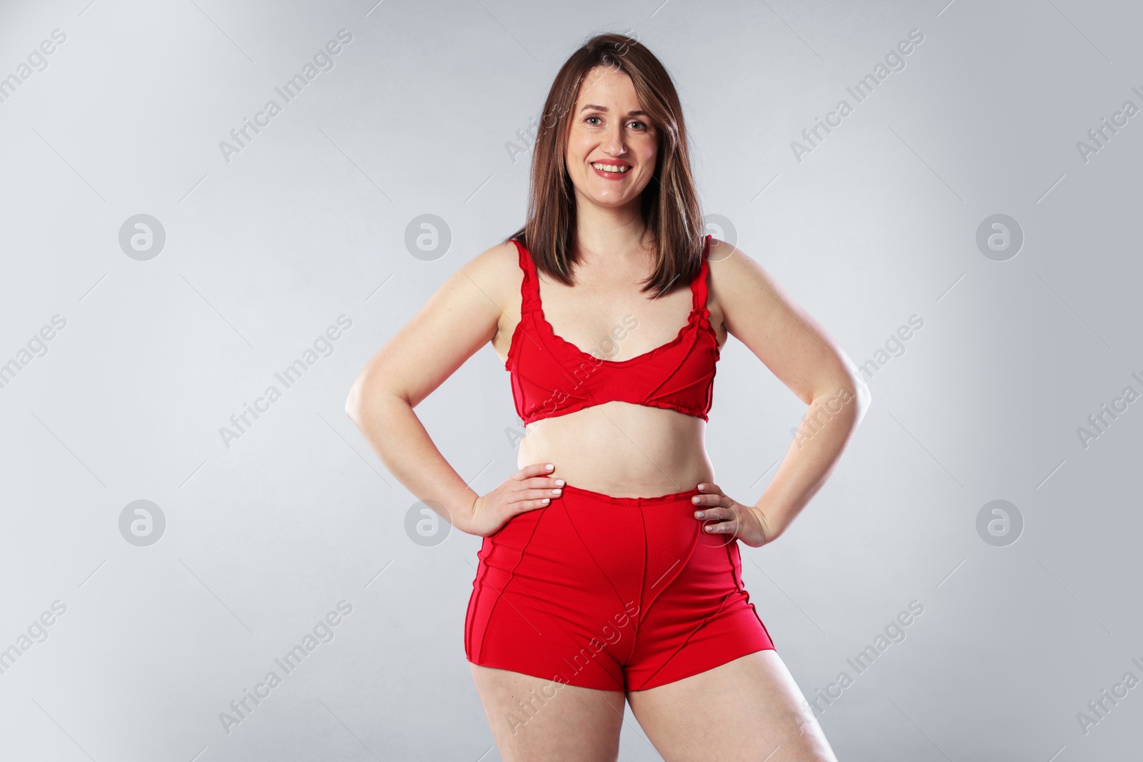 Photo of Woman in red underwear on light grey background. Cellulite problem