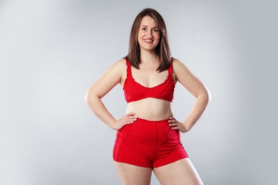 Photo of Woman in red underwear on light grey background. Cellulite problem