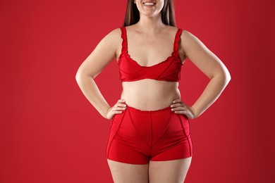 Woman in underwear on red background, closeup. Cellulite problem