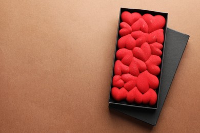 Photo of Chocolate bar decorated with hearts on brown background, top view. Space for text