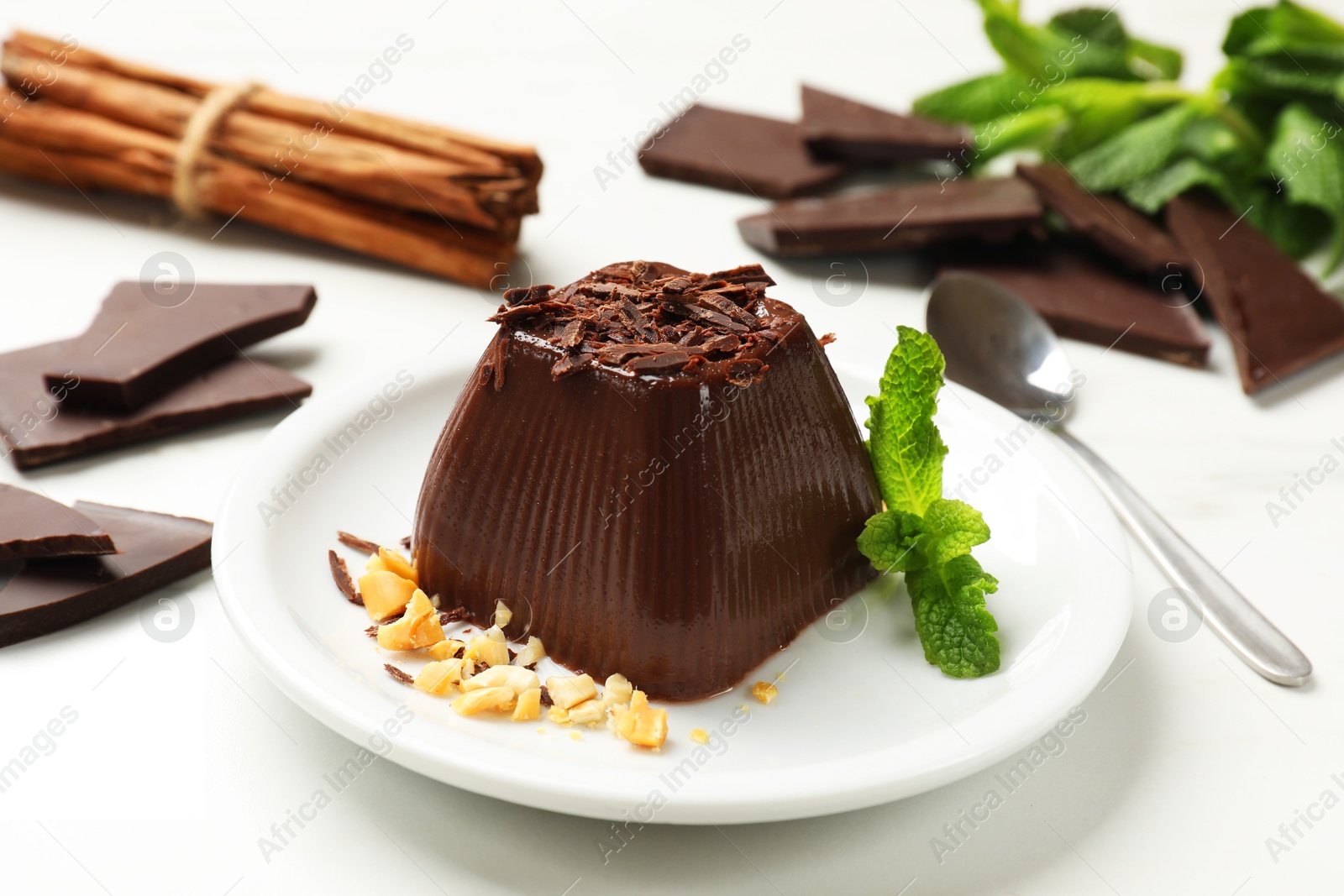 Photo of Tasty chocolate pudding with peanuts and mint on white table