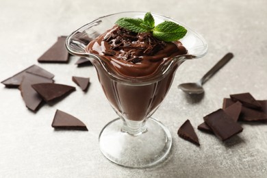 Photo of Delicious chocolate mousse in glass dessert bowl on grey table, closeup