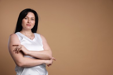 Portrait of charming plus size model on beige background, space for text. Overweight