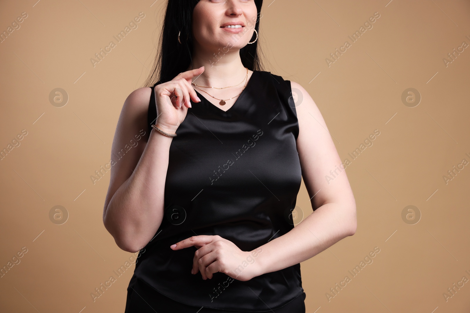 Photo of Smiling plus size model on beige background, closeup. Overweight