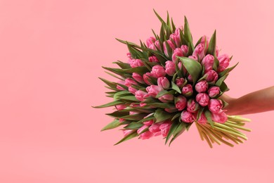 Woman with bouquet of beautiful tulips on pink background, closeup. Space for text