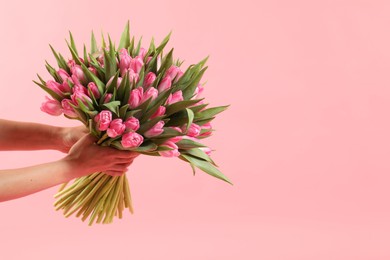 Woman with bouquet of beautiful tulips on pink background, closeup. Space for text