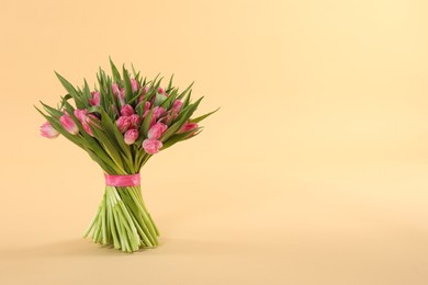 Photo of Bouquet of beautiful tulips on beige background, space for text