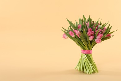 Photo of Bouquet of beautiful tulips on beige background, space for text