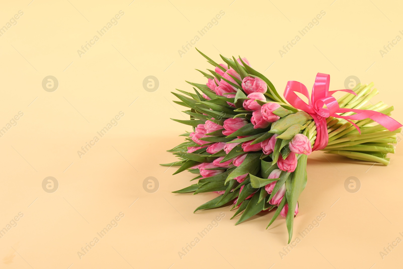 Photo of Bouquet of beautiful tulips on beige background, space for text