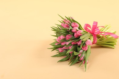 Photo of Bouquet of beautiful tulips on beige background, space for text