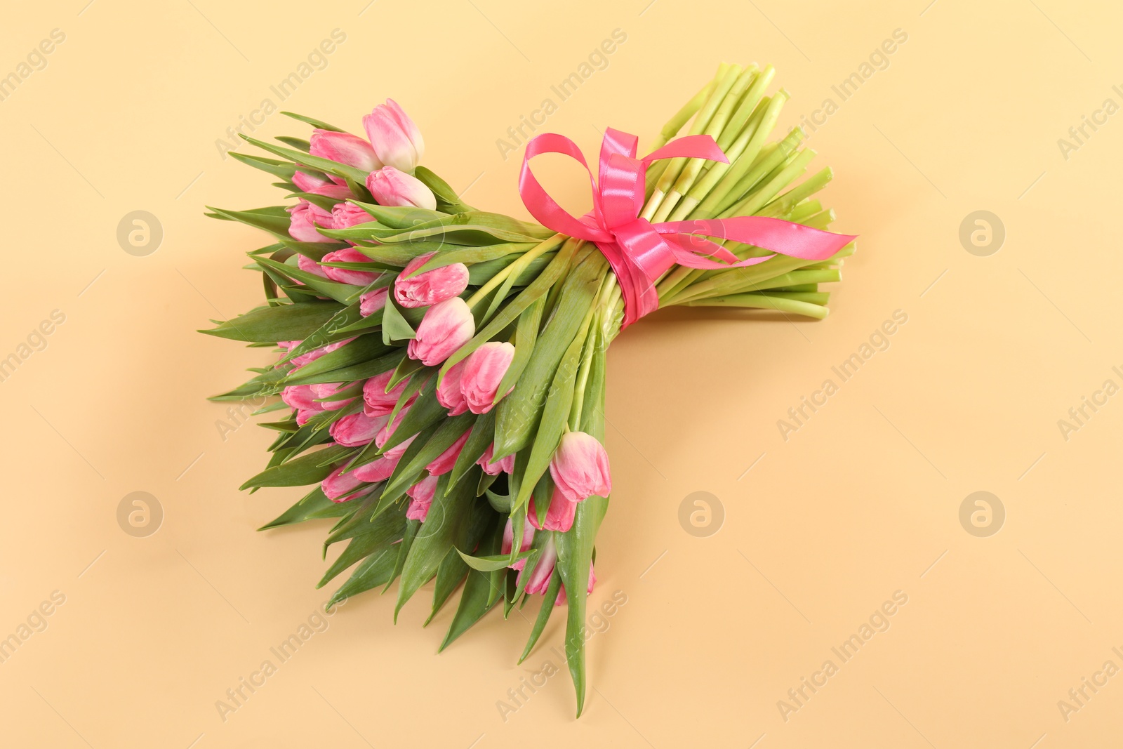 Photo of Bouquet of beautiful tulips on beige background, above view