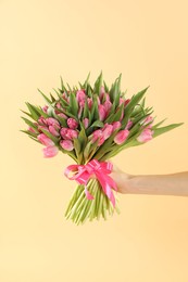 Woman with bouquet of beautiful tulips on beige background, closeup