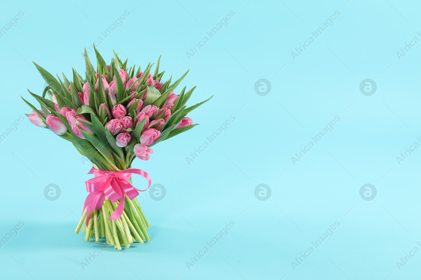 Photo of Bouquet of beautiful tulips on light blue background, space for text