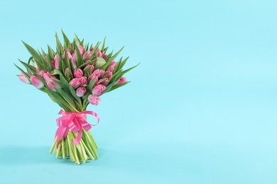 Photo of Bouquet of beautiful tulips on light blue background, space for text