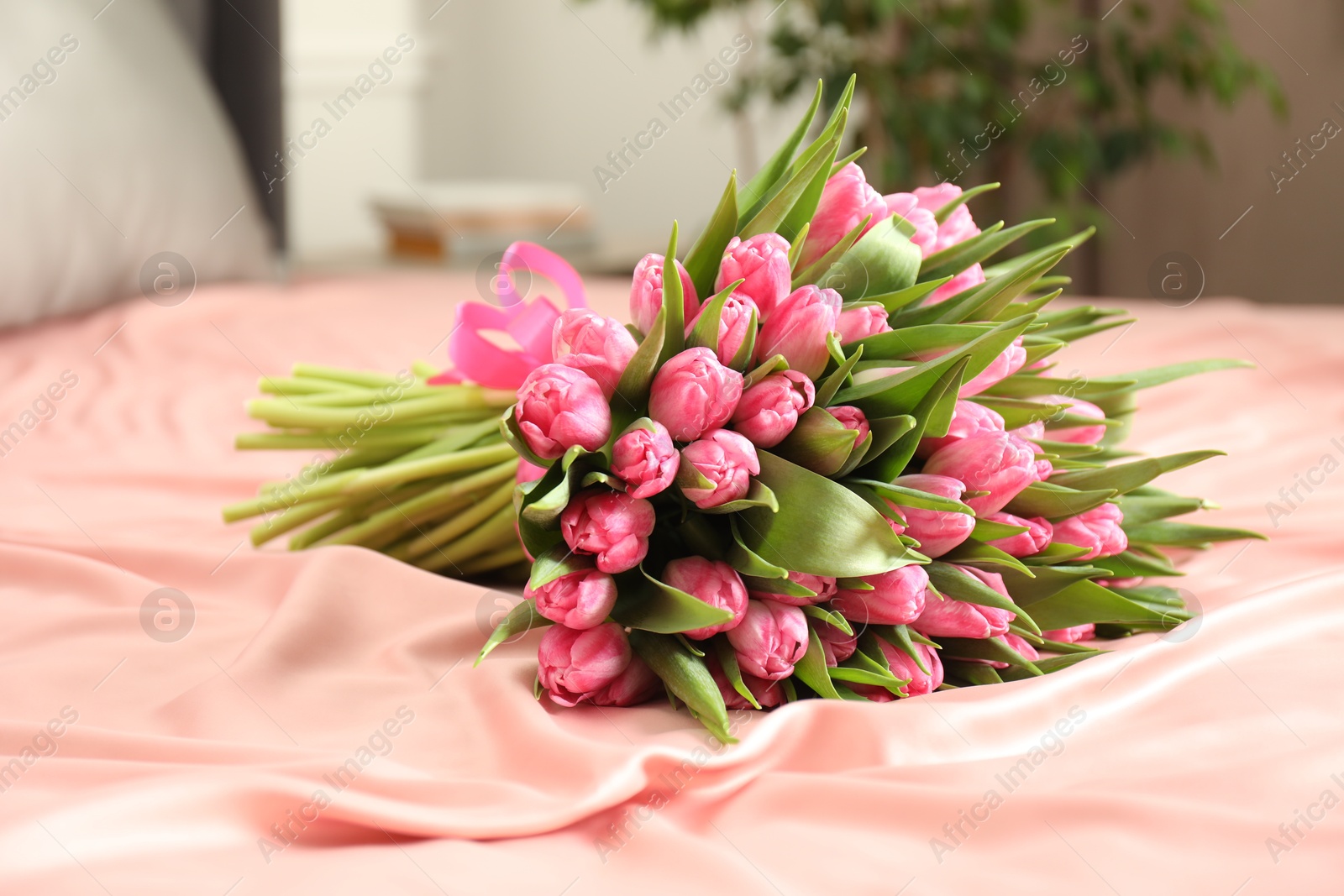 Photo of Bouquet of beautiful tulips on bed indoors