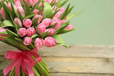 Bouquet of beautiful tulips on wooden table against pale green background, closeup. Space for text