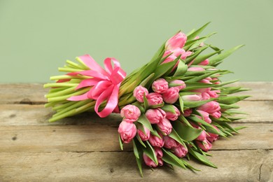 Bouquet of beautiful tulips on wooden table against pale green background