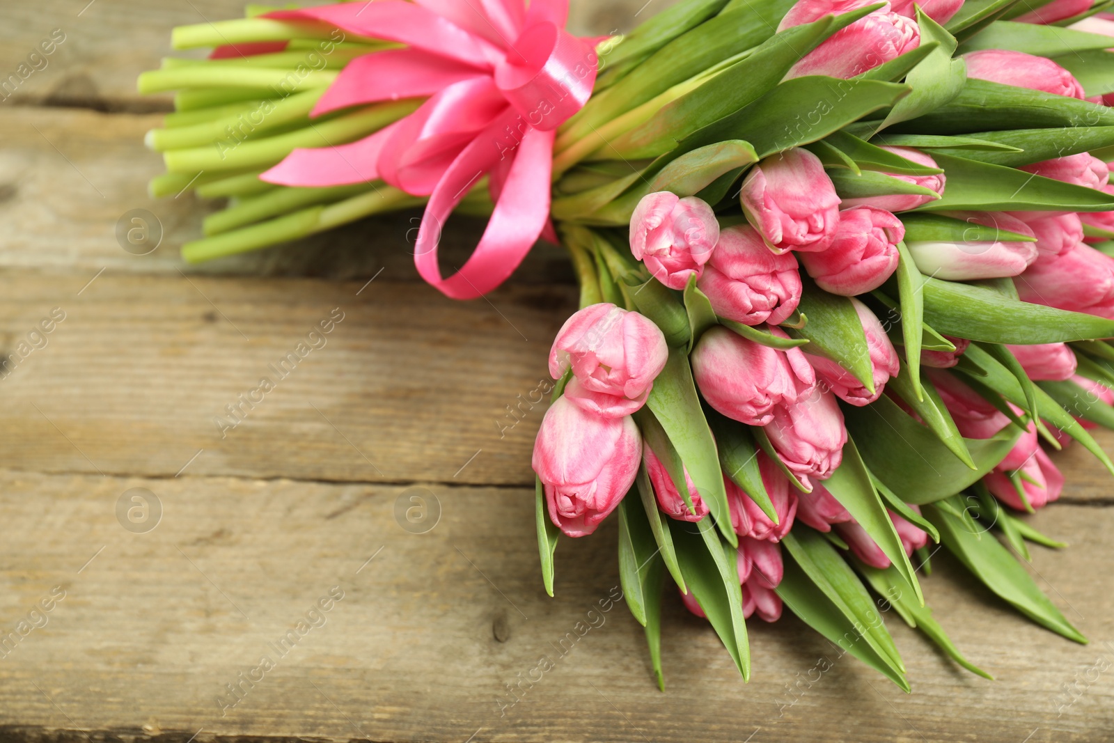 Photo of Bouquet of beautiful tulips on wooden table, closeup. Space for text