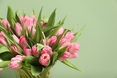 Photo of Bouquet of beautiful tulips on pale green background, closeup. Space for text