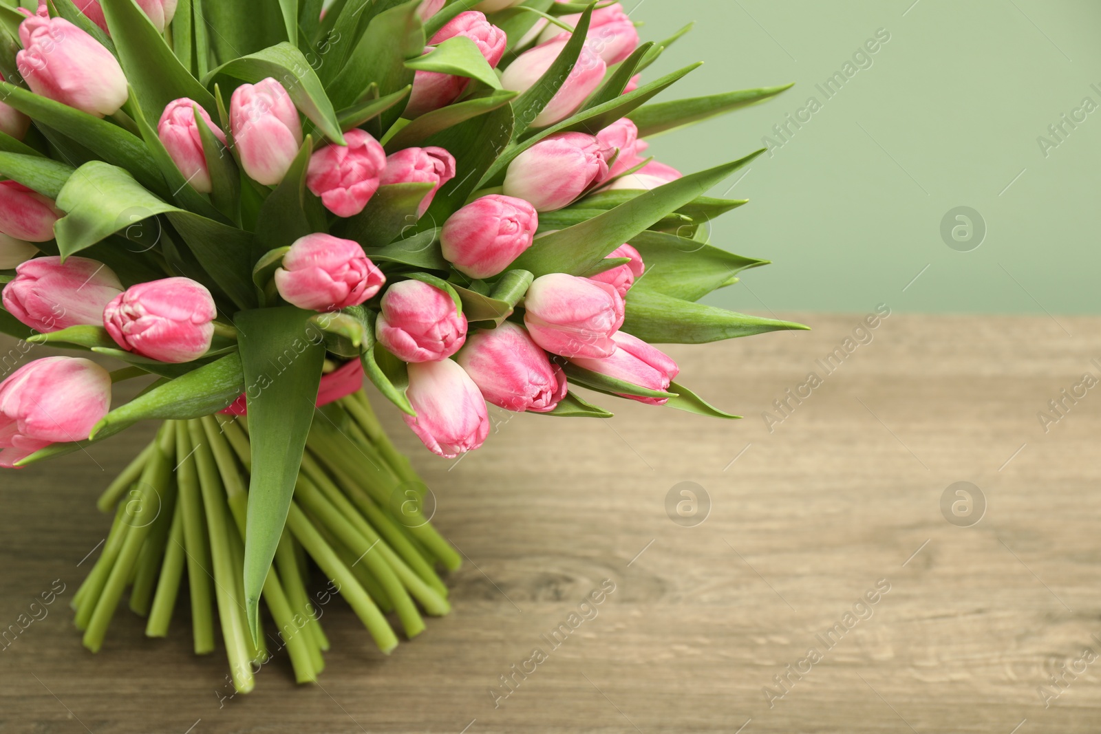 Photo of Bouquet of beautiful tulips on wooden table, closeup. Space for text