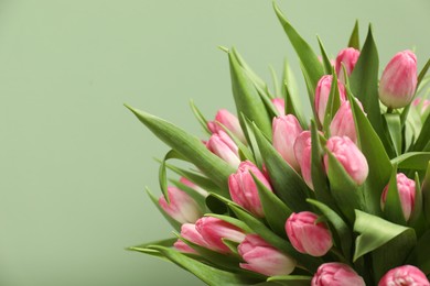 Photo of Bouquet of beautiful tulips on pale green background, closeup. Space for text