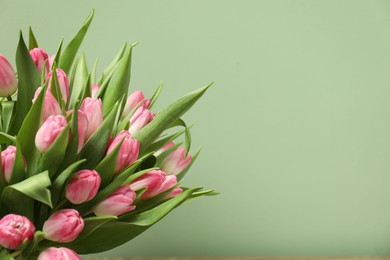 Photo of Bouquet of beautiful tulips on pale green background, closeup. Space for text