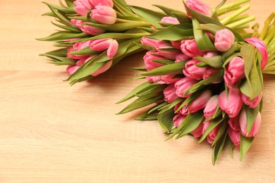 Photo of Bouquets of beautiful tulips on wooden table, closeup. Space for text