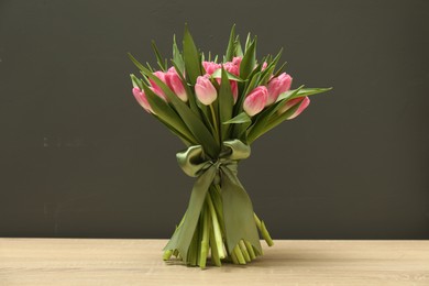 Bouquet of beautiful tulips on wooden table against grey background