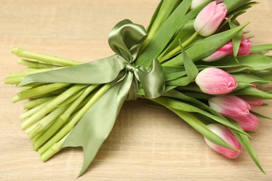 Photo of Bouquet of beautiful tulips on wooden table, closeup