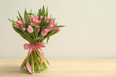 Photo of Bouquet of beautiful tulips on wooden table against light grey background, space for text