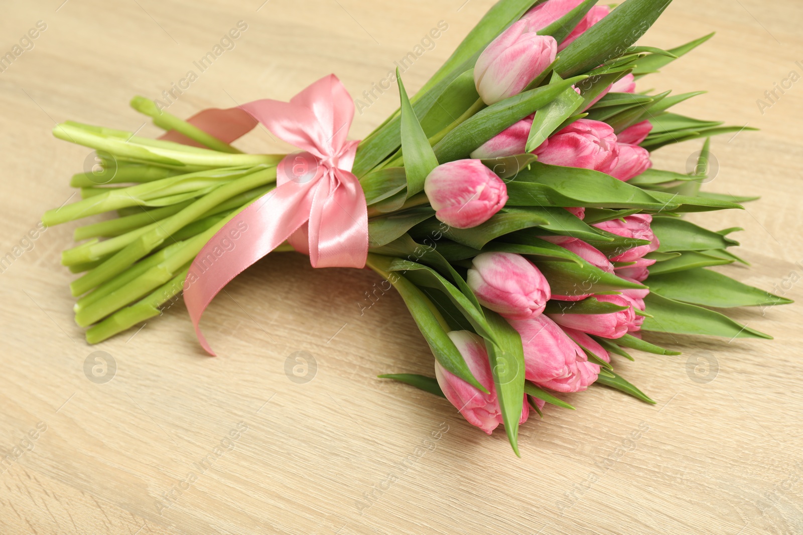 Photo of Bouquet of beautiful tulips on wooden table, closeup