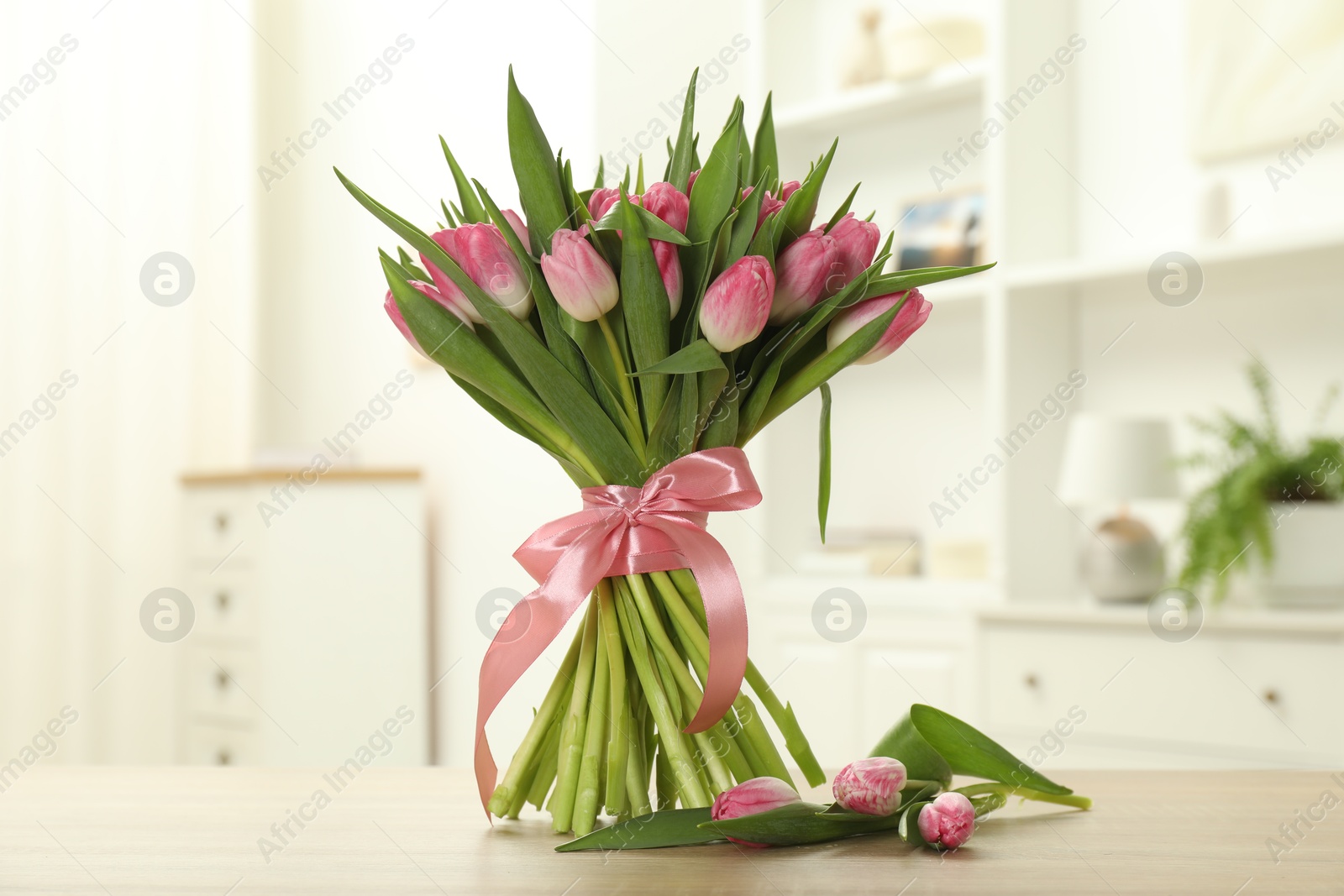 Photo of Bouquet of beautiful tulips on wooden table indoors