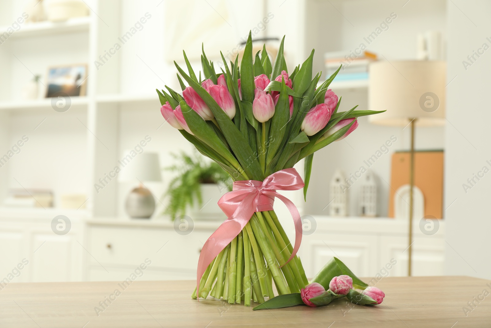 Photo of Bouquet of beautiful tulips on wooden table indoors