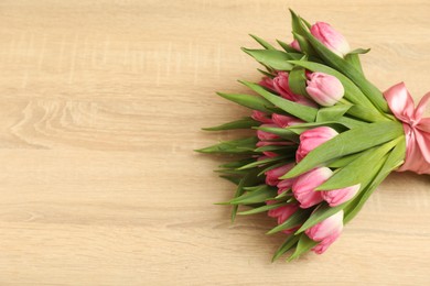 Photo of Bouquet of beautiful tulips on wooden table, above view. Space for text