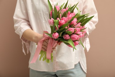 Woman with bouquet of beautiful tulips on dark beige background, closeup