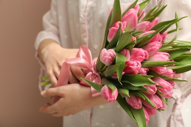 Woman with bouquet of beautiful tulips on dark beige background, closeup