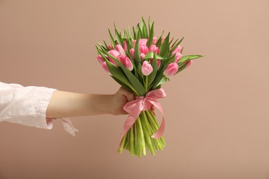 Woman with bouquet of beautiful tulips on dark beige background, closeup