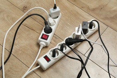 Photo of Extension power boards overloaded with plugs on wooden floor