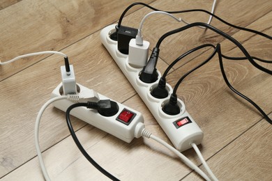 Photo of Extension power boards overloaded with plugs on wooden floor